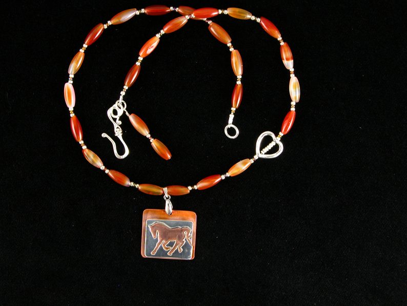 Sterling cut out horse on heat patinaed copper on necklace of carnelian beads