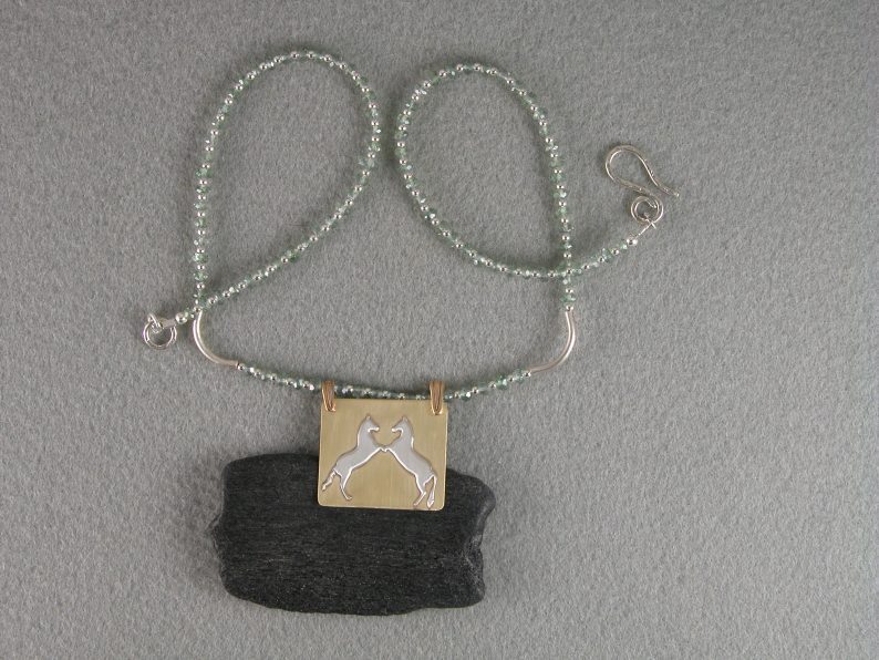 Two sterling rearing horses on brass pendant